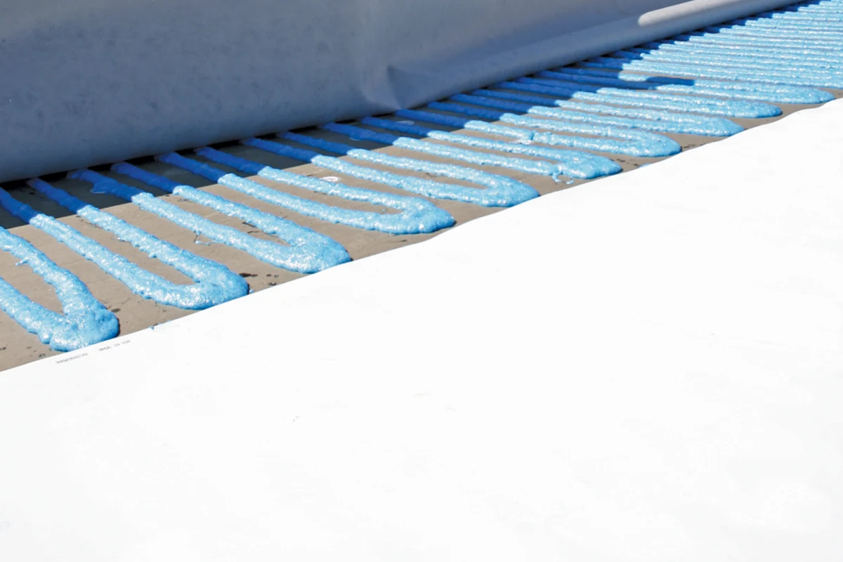 Crew installing a Carlisle FleeceBACK TPO roofing system with Flexible FAST adhesive