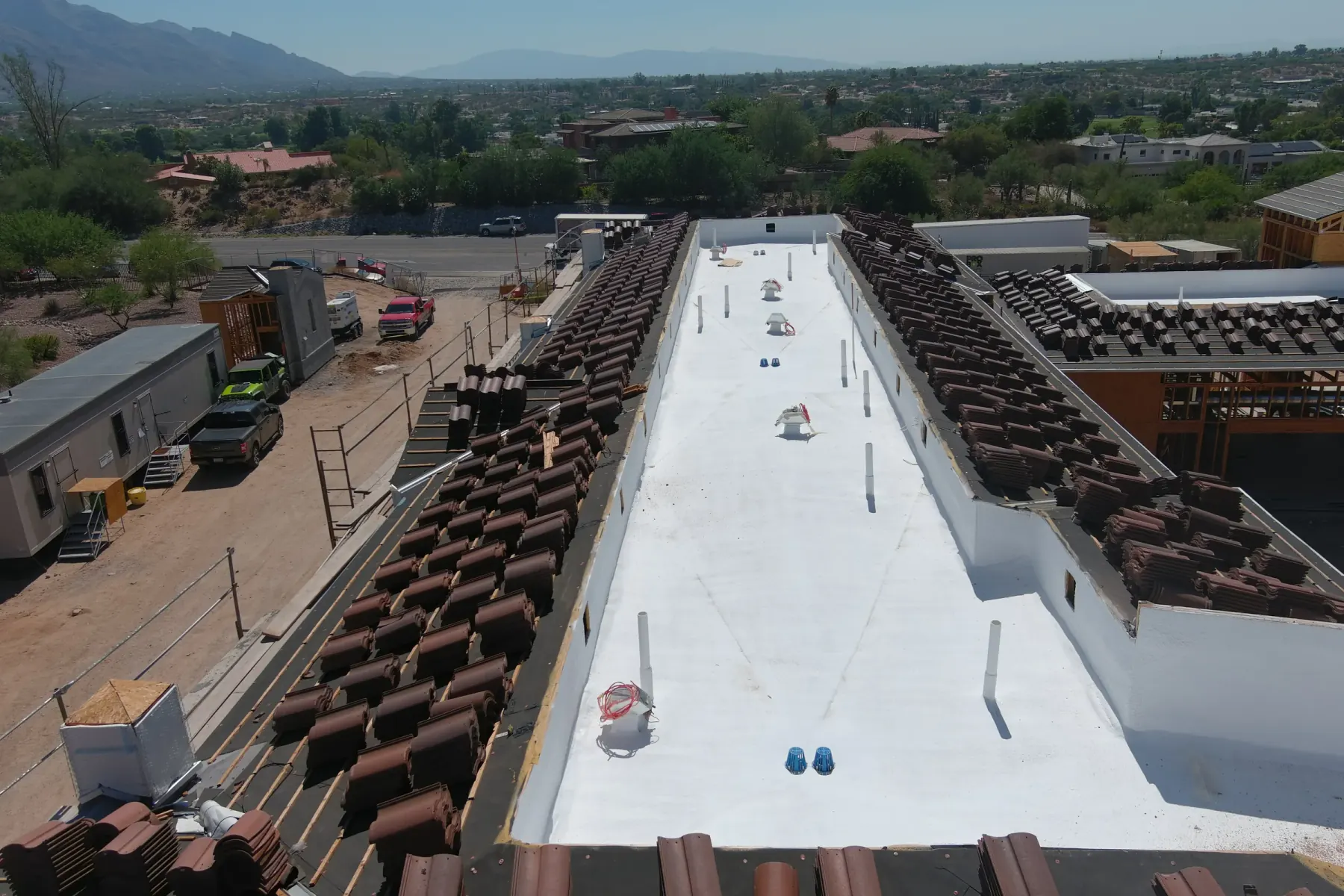 White low-slope roof beside pitched tile construction