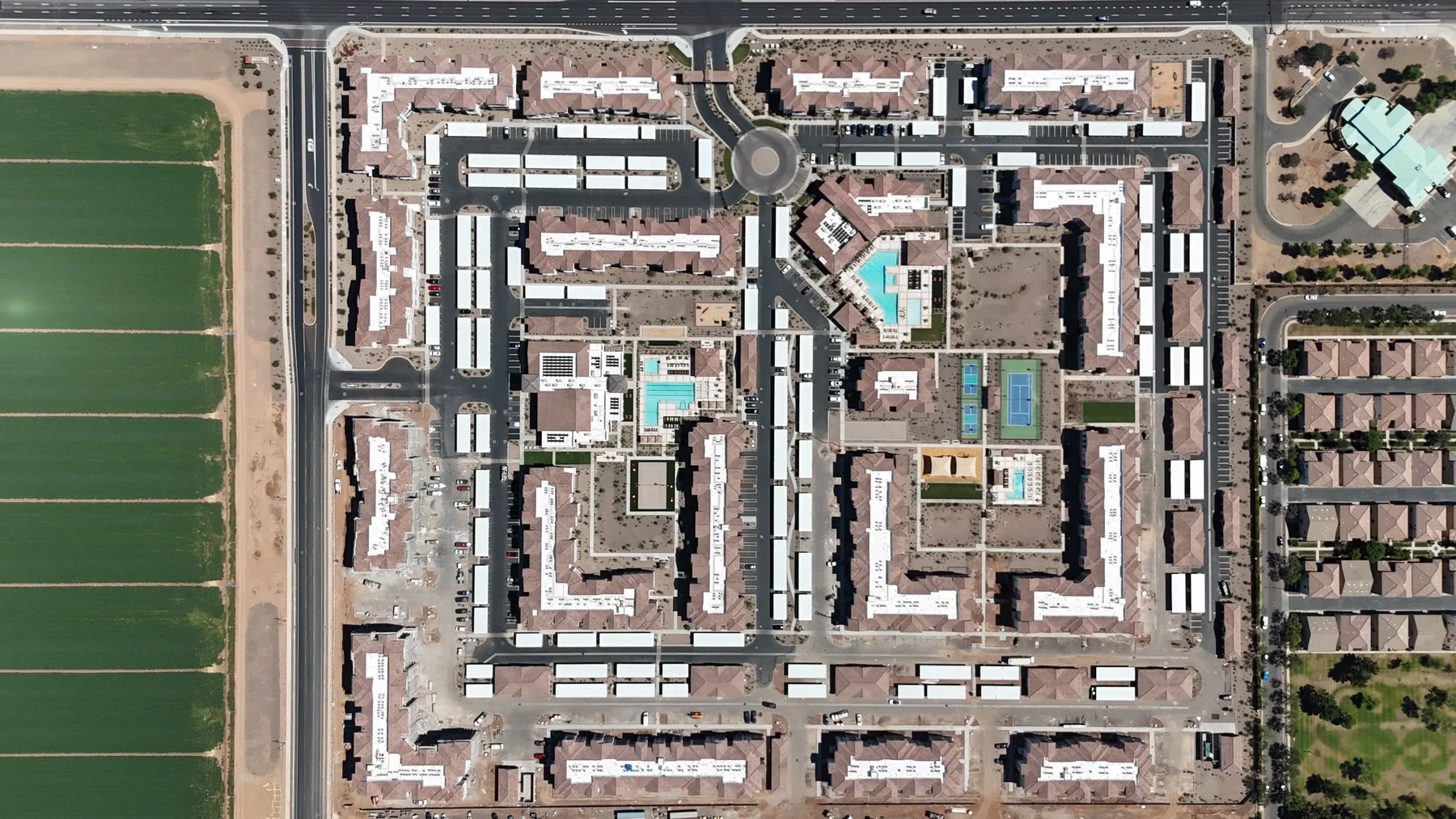 Vertical aerial view of reddish tile and white low-slope roofs surrounding courtyards and turquoise pools
