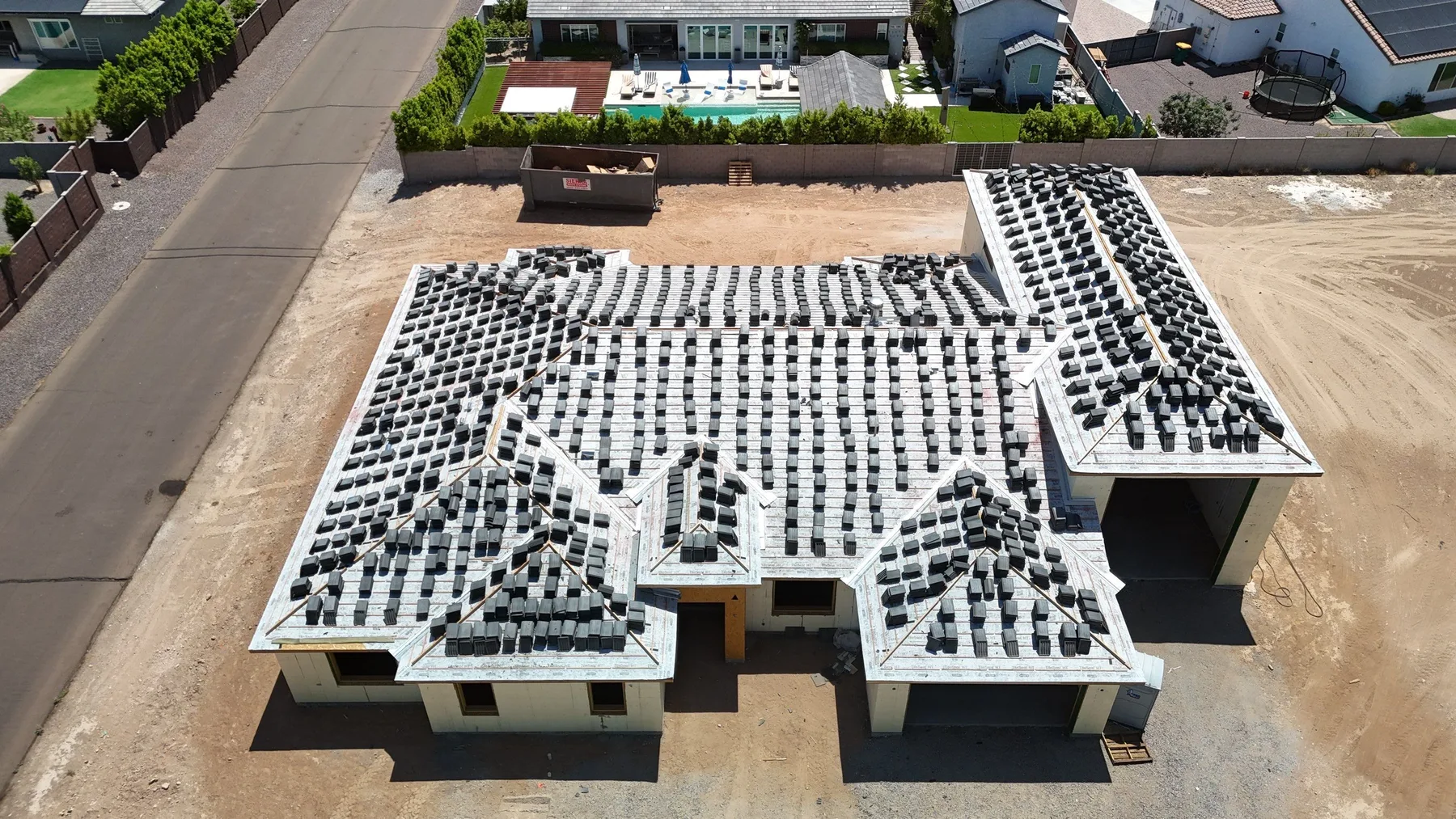 Oblique aerial view of white roof base, black battens, and stacked gray tiles awaiting installation