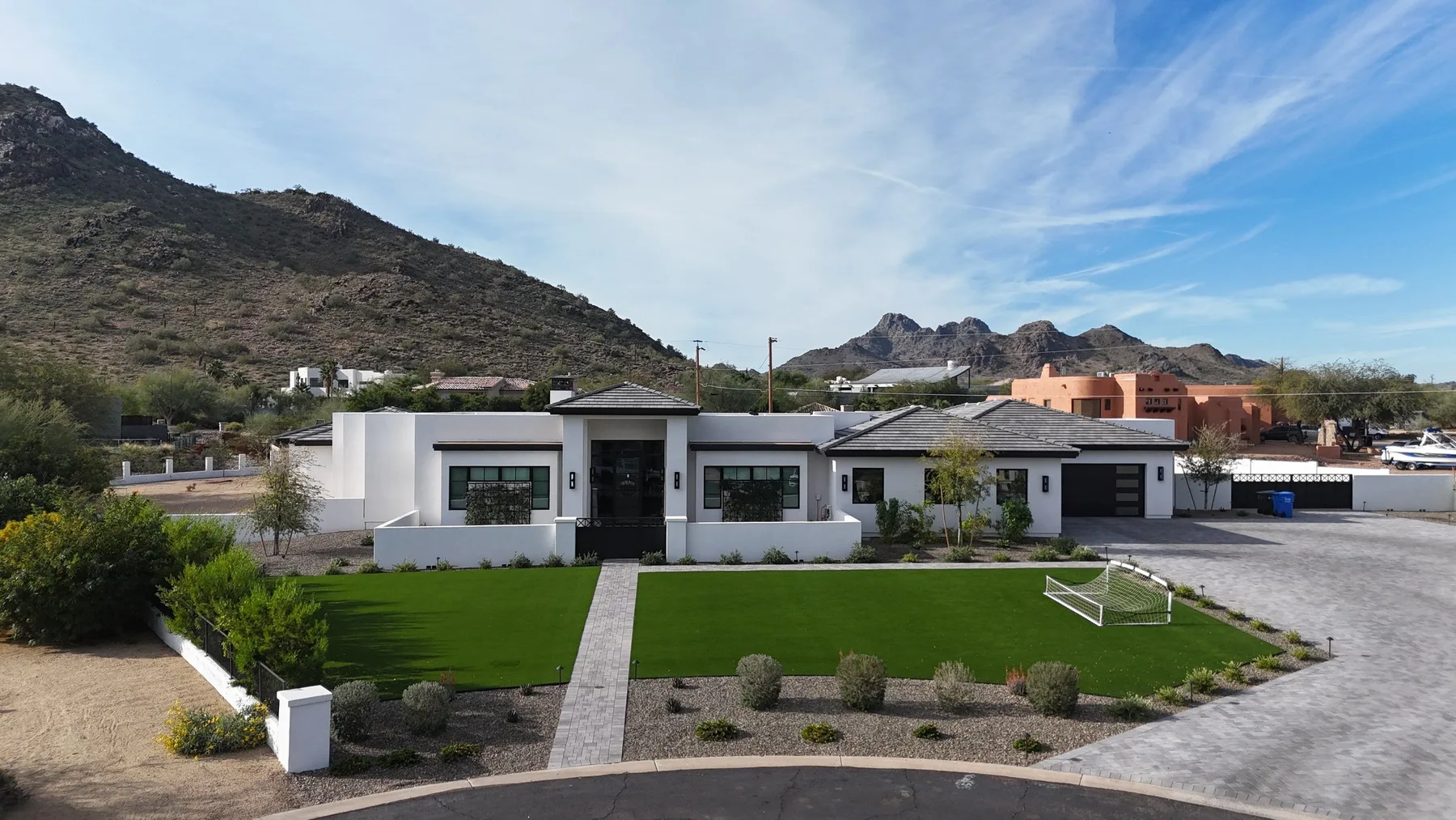 Ground-level front view of white flat and gray tiled roofs above a landscaped residence