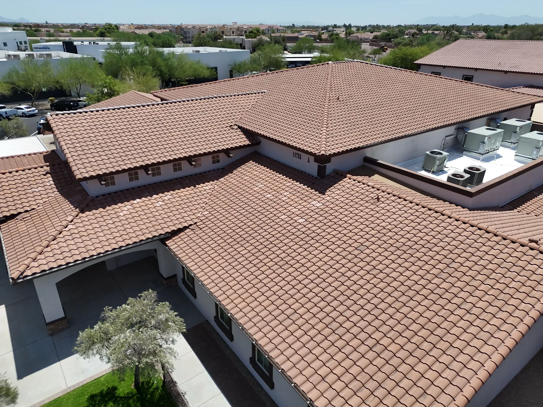 Oblique aerial view of completed terracotta tile roofs surrounding a white equipment platform