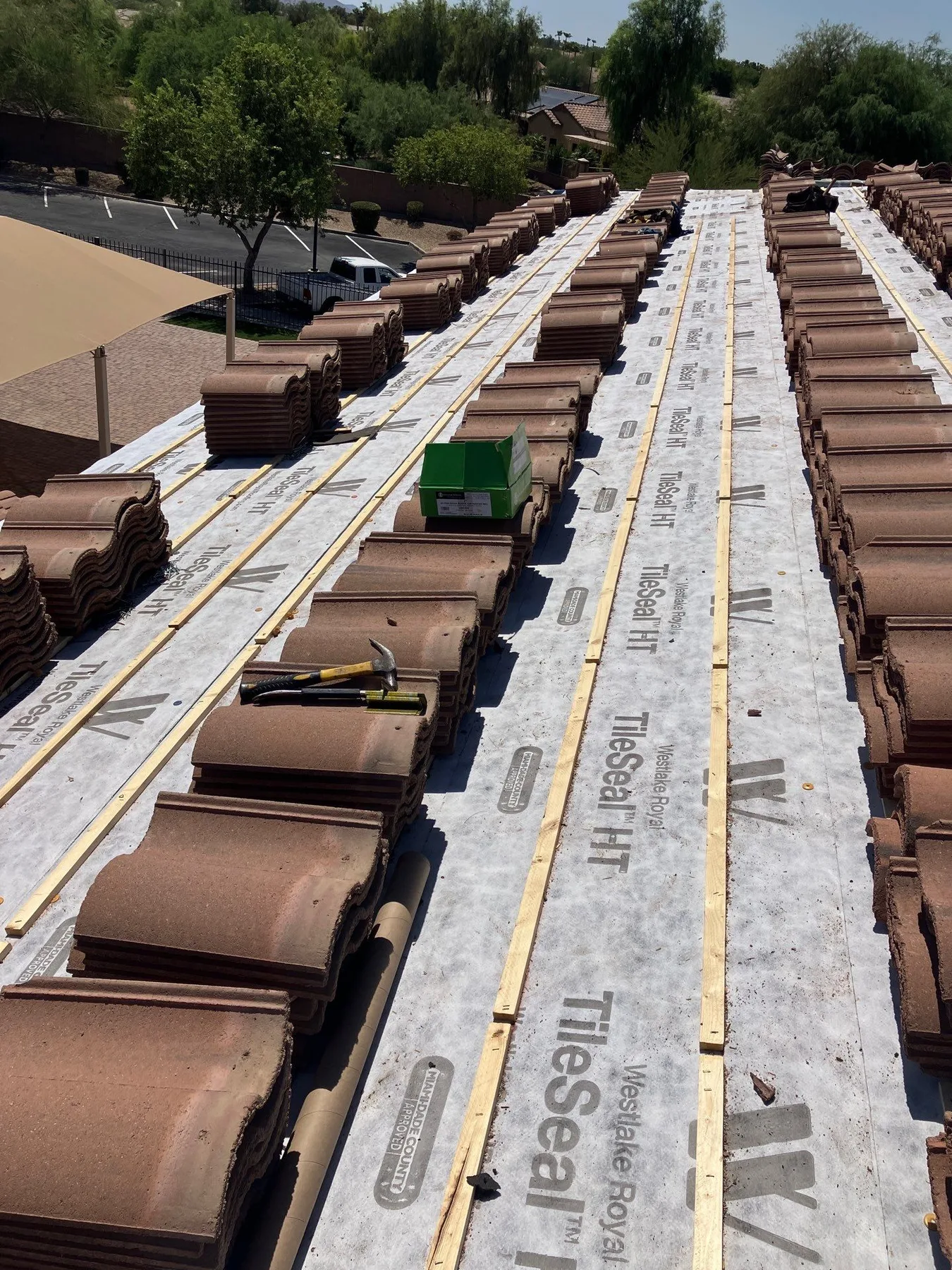 Rooftop perspective along white underlayment with brown tile stacks bordering a central valley