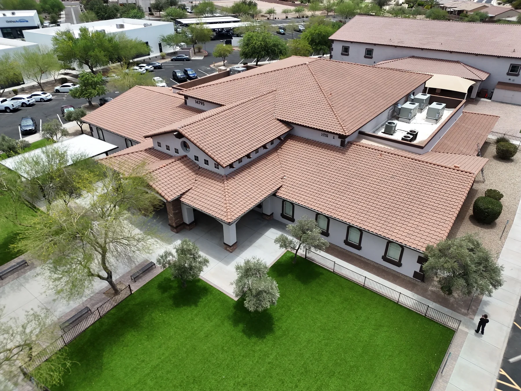 Oblique aerial view of completed terracotta tile roof with white equipment well and green lawn