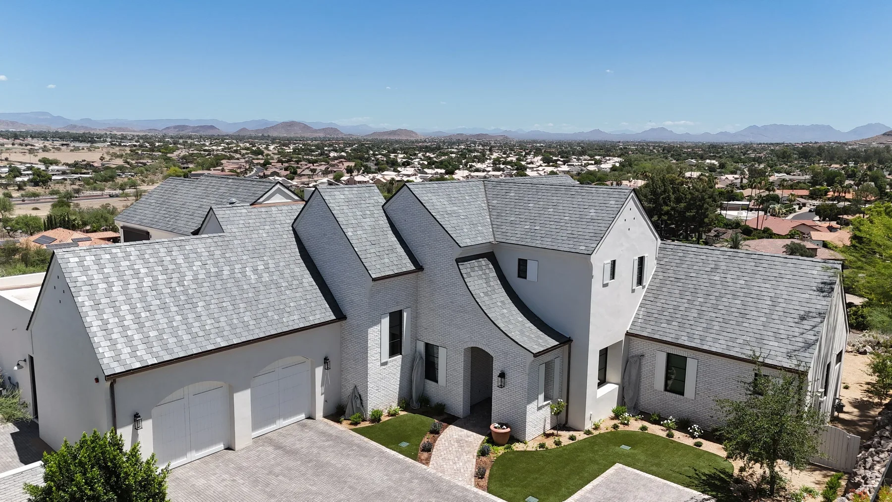 Wide aerial view of gray slate-style gabled roofing on a white two-story house