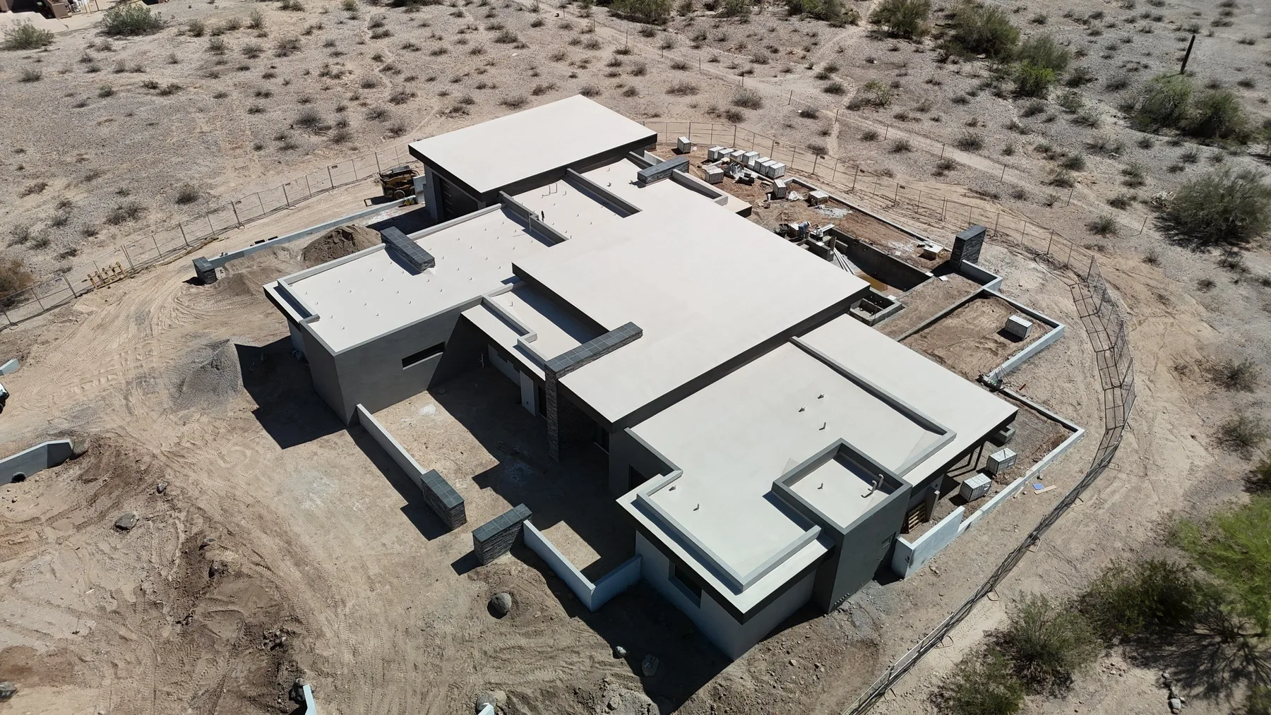 High aerial view of light gray flat and low-slope roofs on an angular desert property