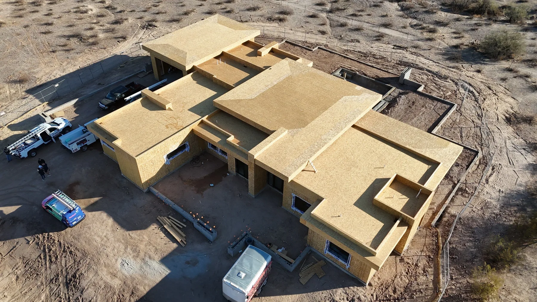 Oblique aerial view of tan roof sheathing under construction across multiple stepped sections