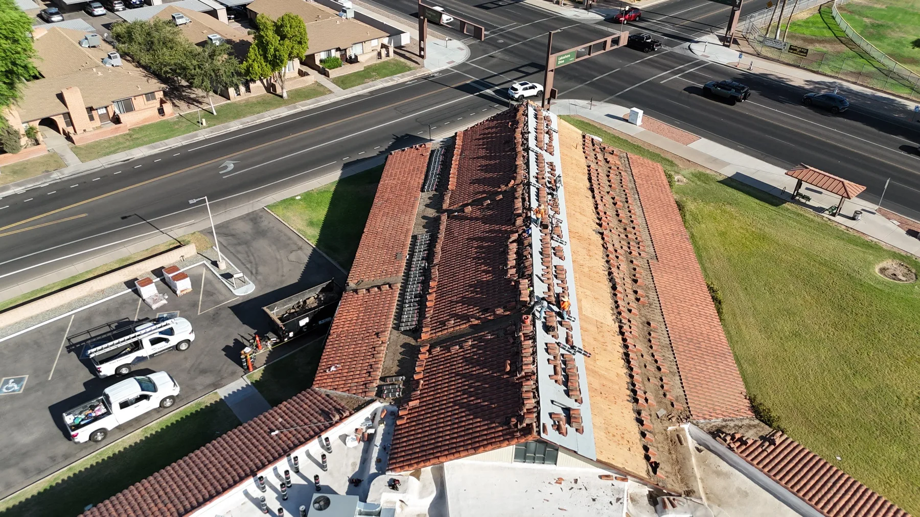 Steep aerial view along a red tile roof with central tan and white work strips