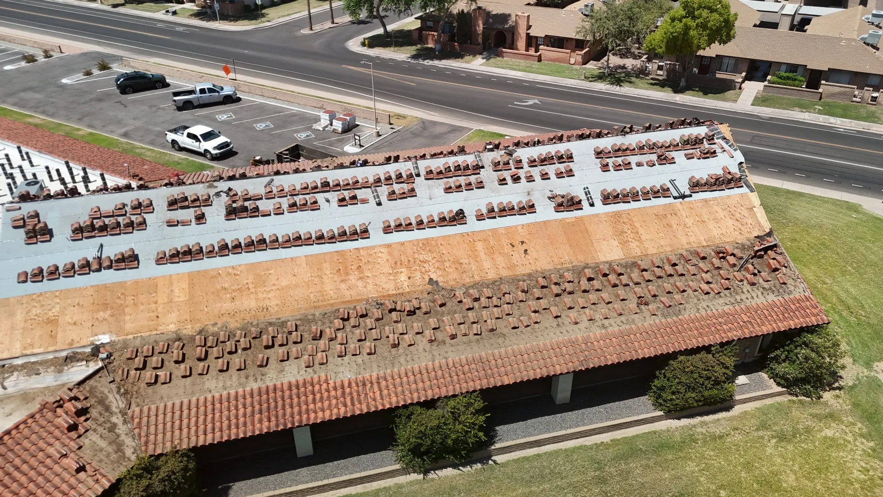 Oblique aerial view of long red tile roof with white underlayment and staged tiles