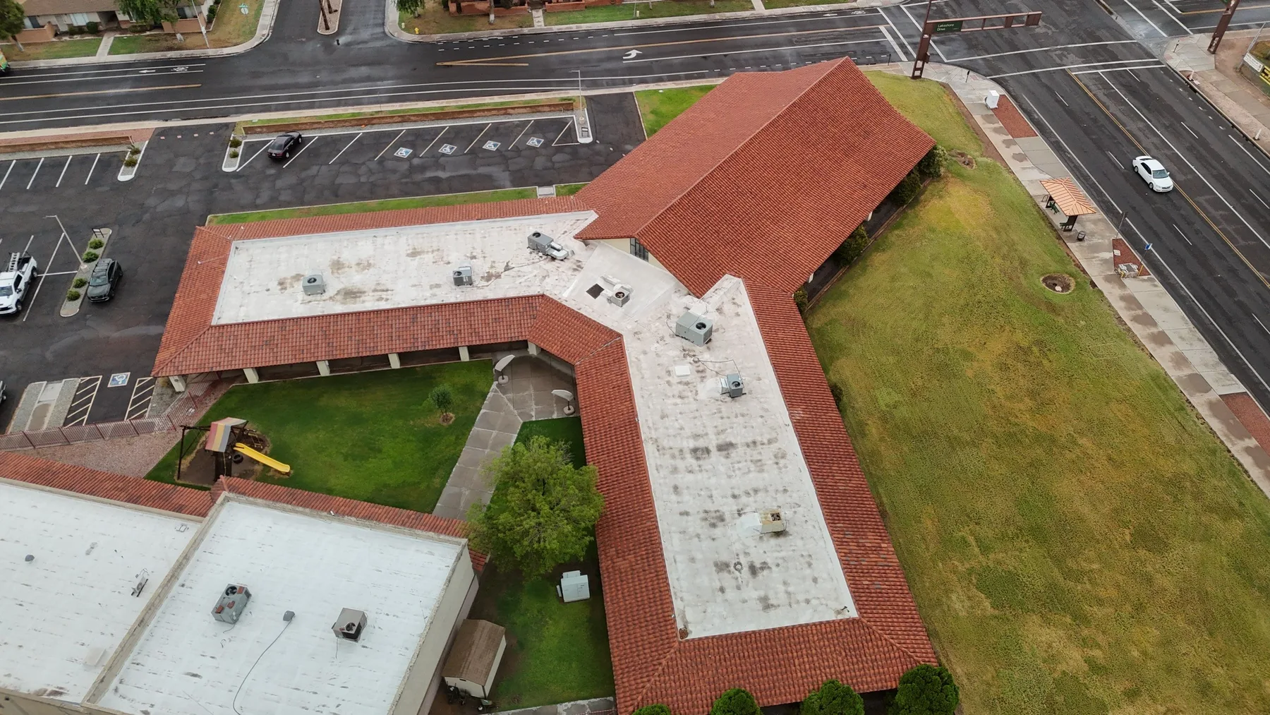 High aerial view of red tile wings surrounding white flat roof sections and a courtyard