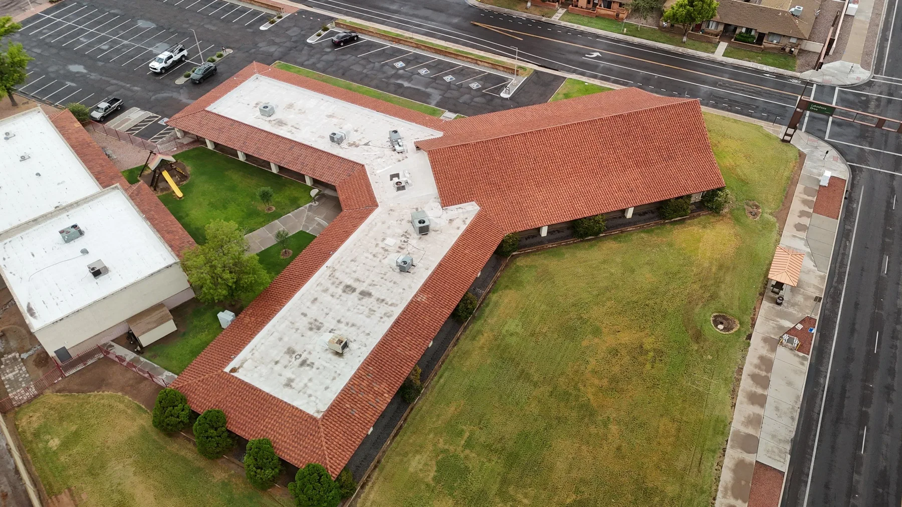 Oblique overhead view of angular red tile wings, white flat roofs, and enclosed lawn