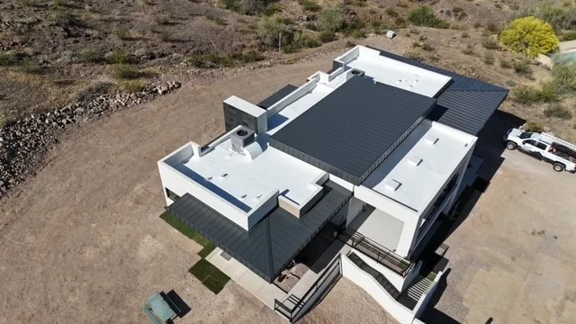 High aerial view of white flat roofs and dark ribbed metal sections on a modern house