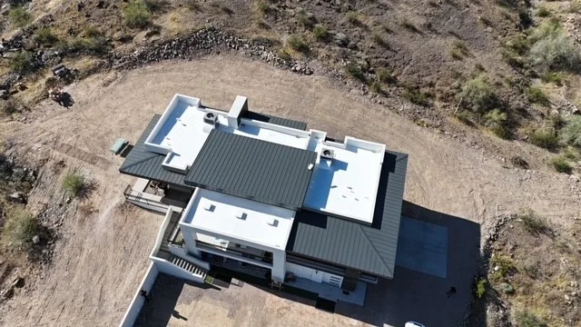 Near-vertical aerial view of central dark metal roofing framed by white flat roof sections