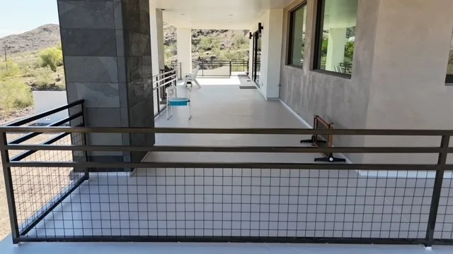 Ground-level view of light gray waterproof walk deck enclosed by black metal railing