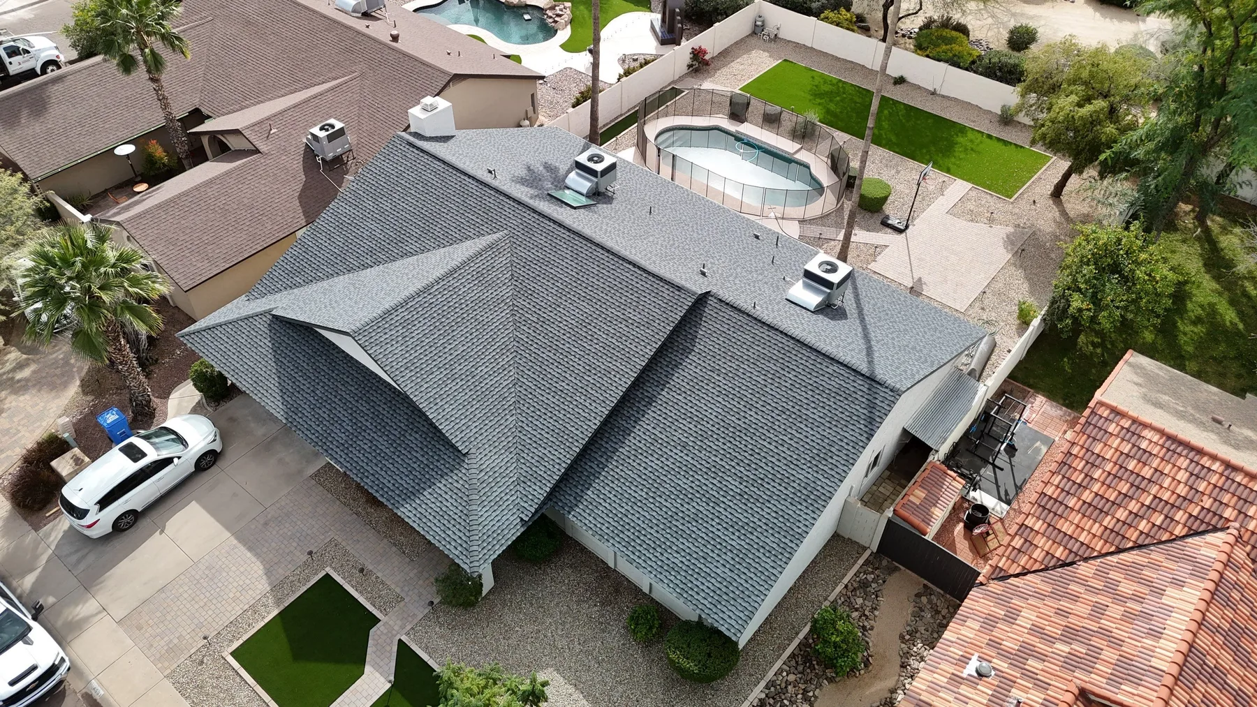 Aerial view of completed gray shingle hip roof with multiple white vent stacks