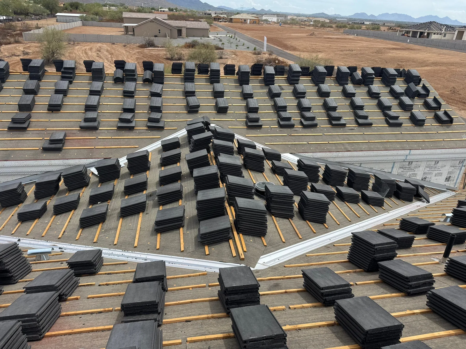 Elevated view of dark tile bundles distributed across battened roof planes and valleys