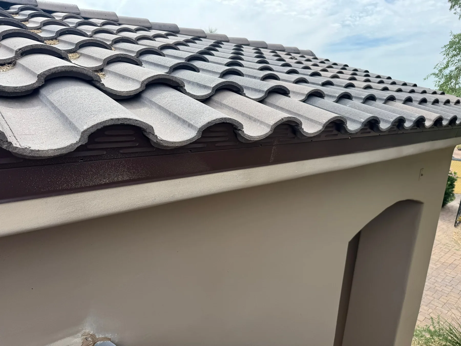 Close angled view of completed gray curved tiles above dark fascia and gutter