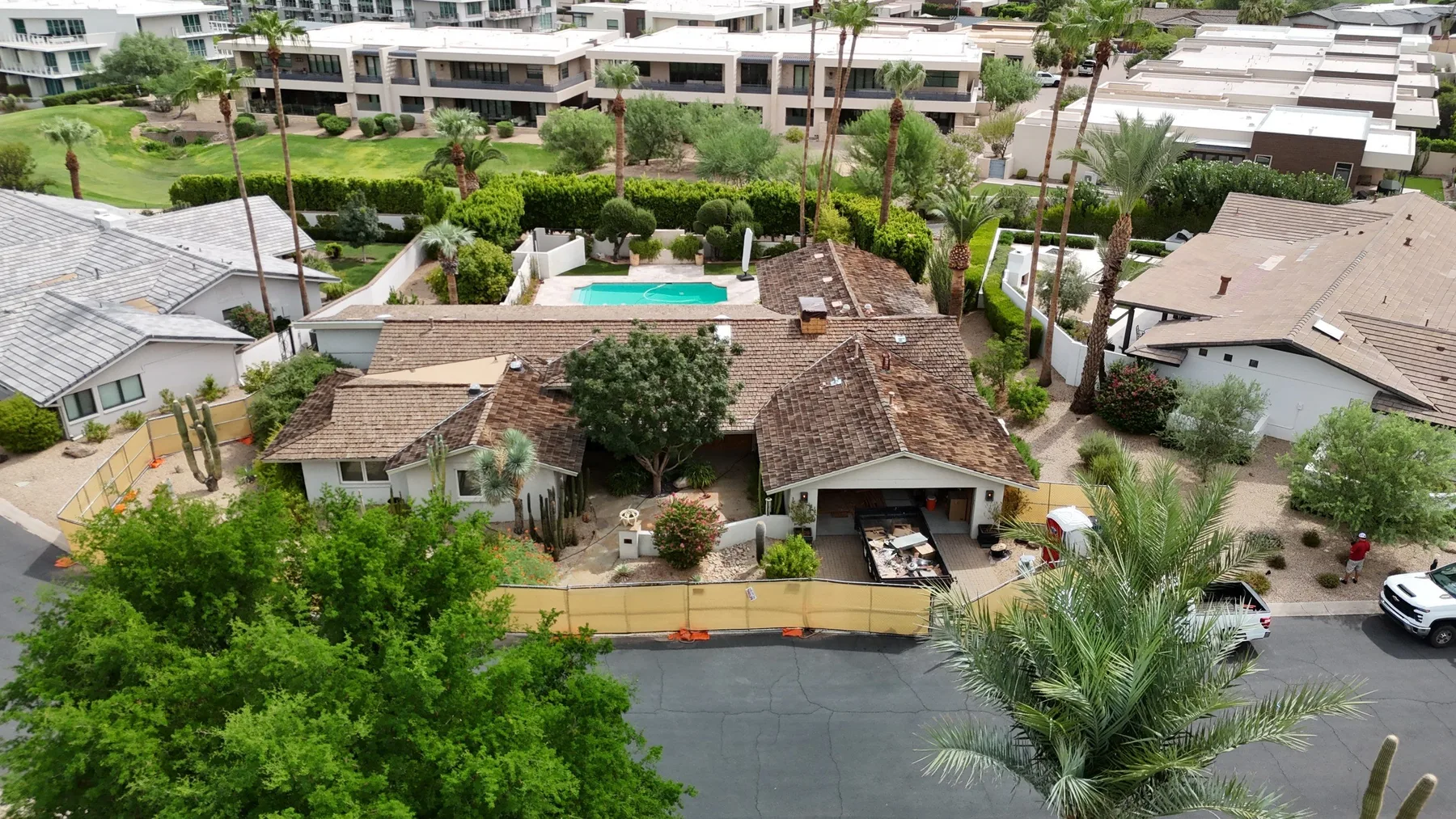 Aerial view of completed mottled brown tile roof with adjacent turquoise courtyard pool