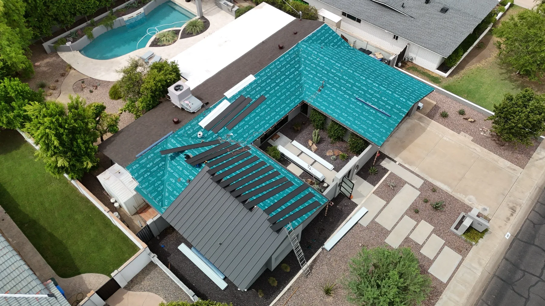 Aerial view of partially installed gray metal roof with turquoise underlayment and exposed battens