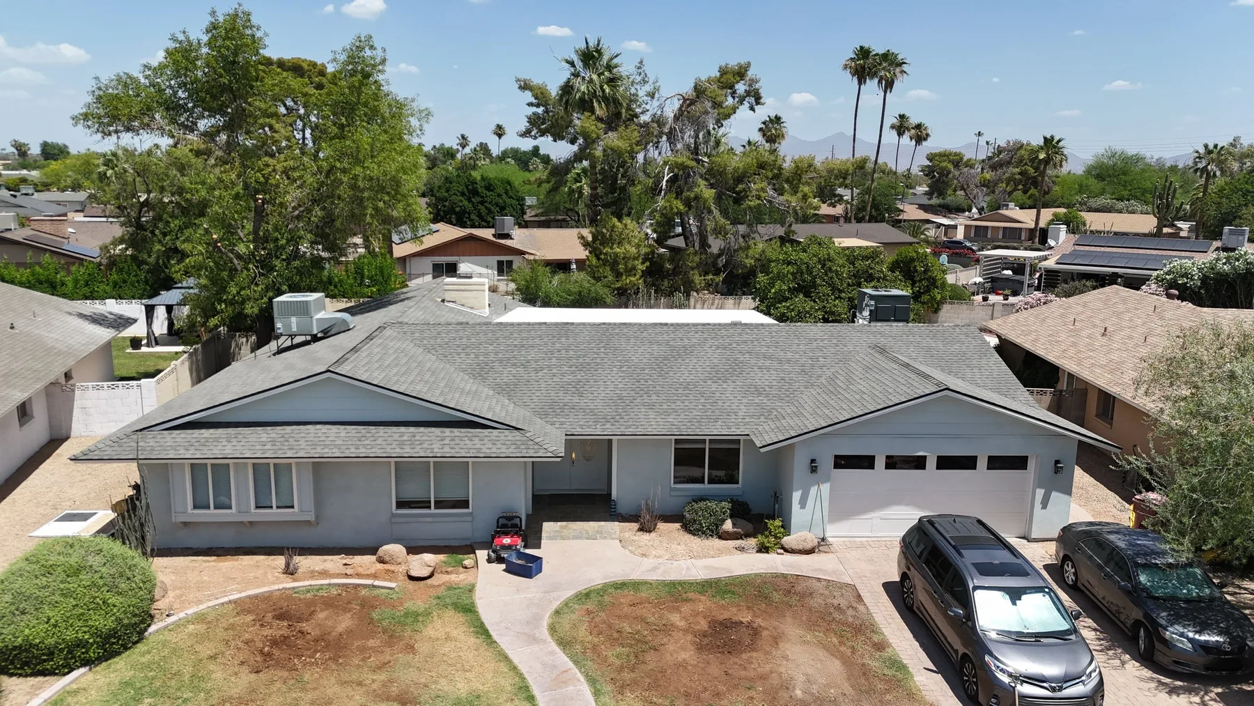 Oblique aerial view of gray shingle roof with attached garage and white flat section