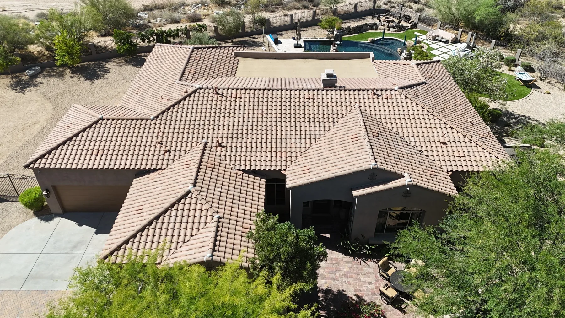 Oblique aerial view of completed tan tile roof with intersecting hips and backyard pool