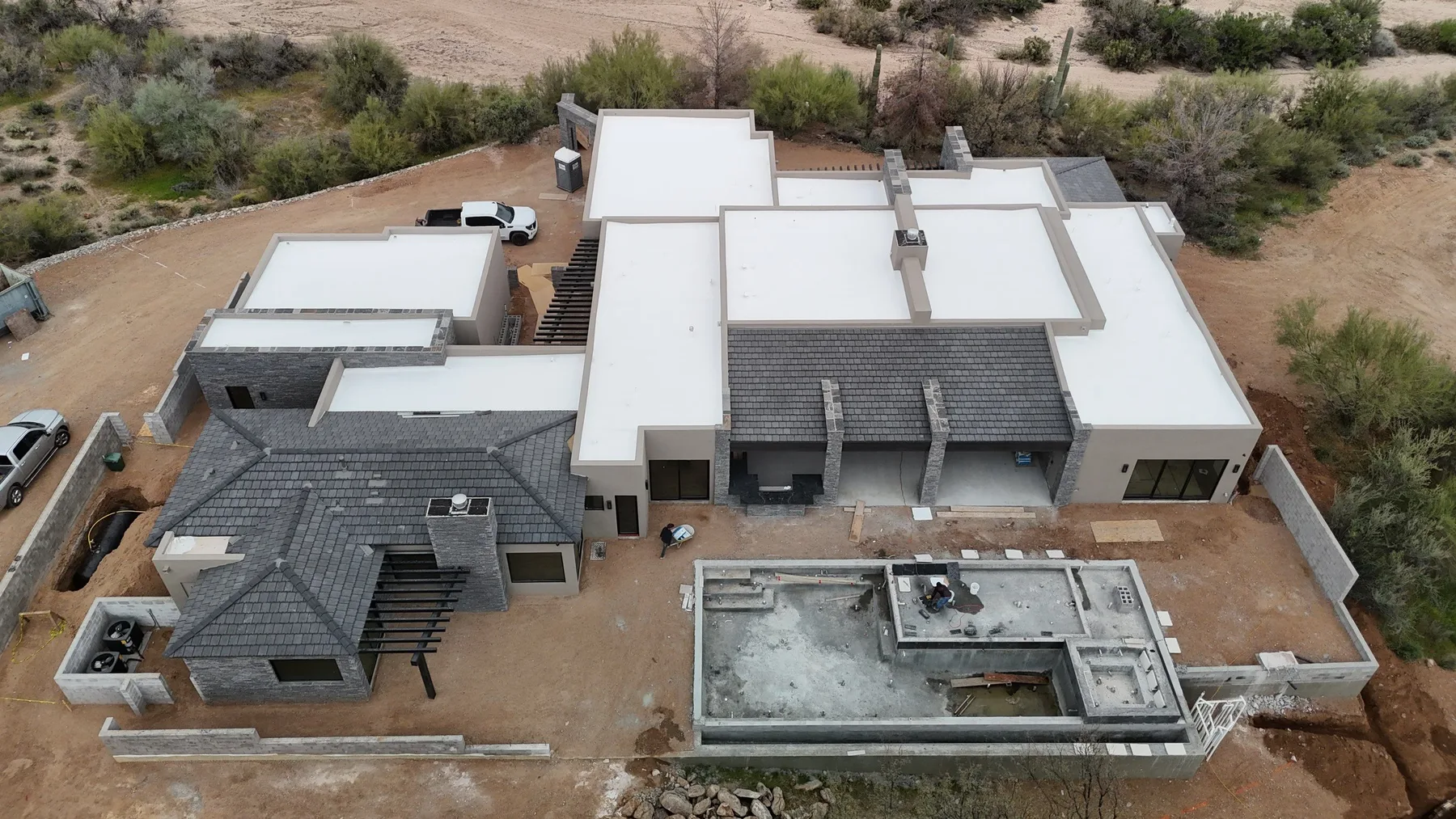High aerial view of mixed white flat and gray shingle roofs with multiple wings