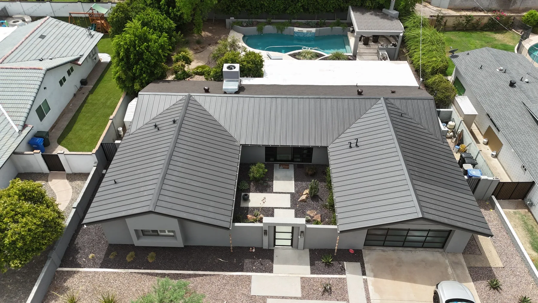 High aerial view of charcoal standing-seam metal roofs surrounding an open central courtyard