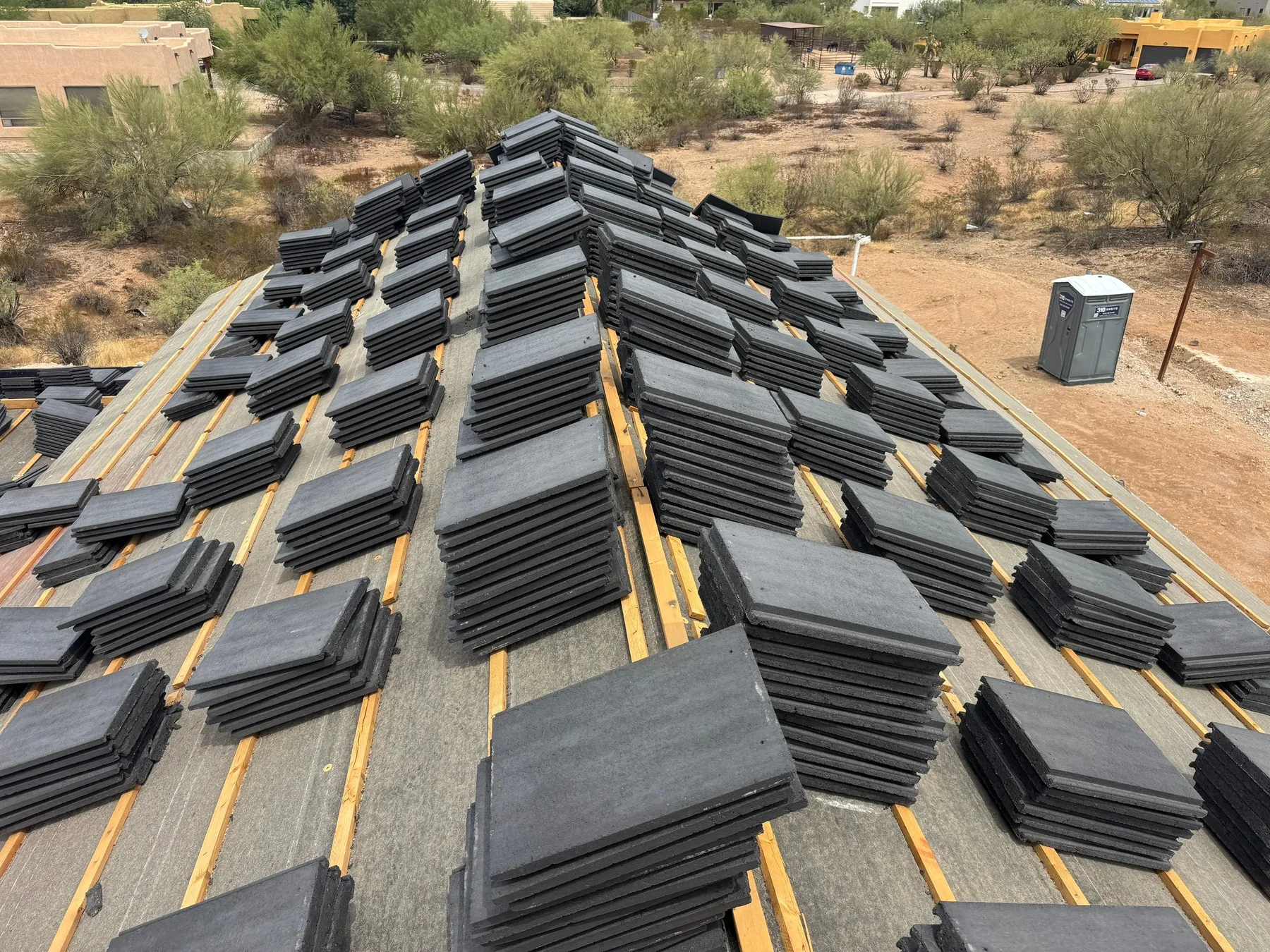 Ridge-level view of black tile stacks arranged along yellow battens on intersecting roof slopes