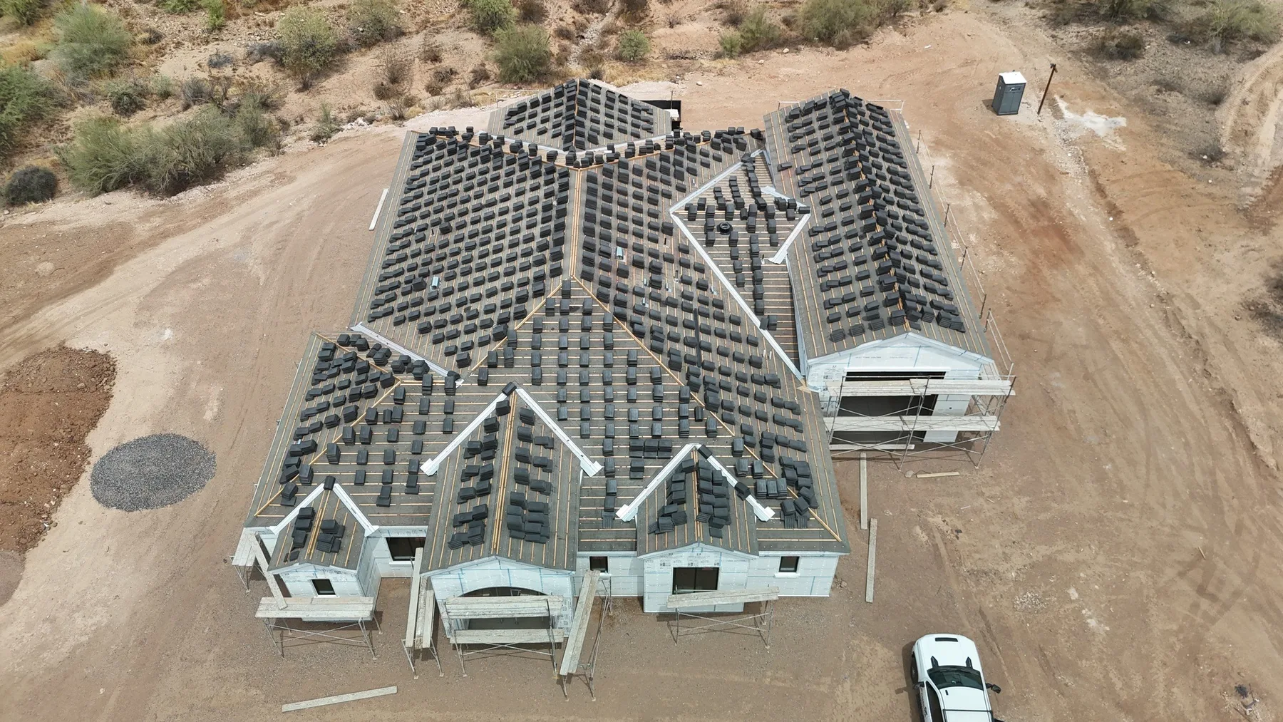 High aerial view of unfinished gray battened roof with numerous gables and white walls