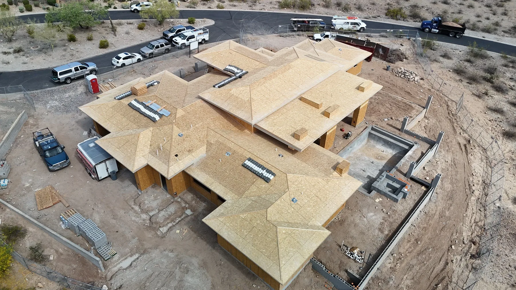 High aerial view of tan plywood roof sheathing with multiple hips and open courtyard