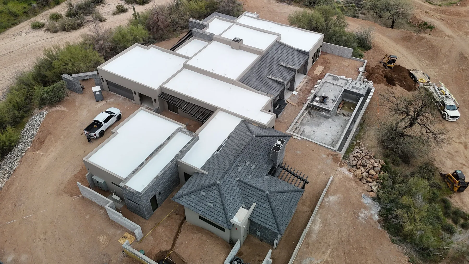 Oblique aerial view of white low-slope roofs and gray tiled hip sections