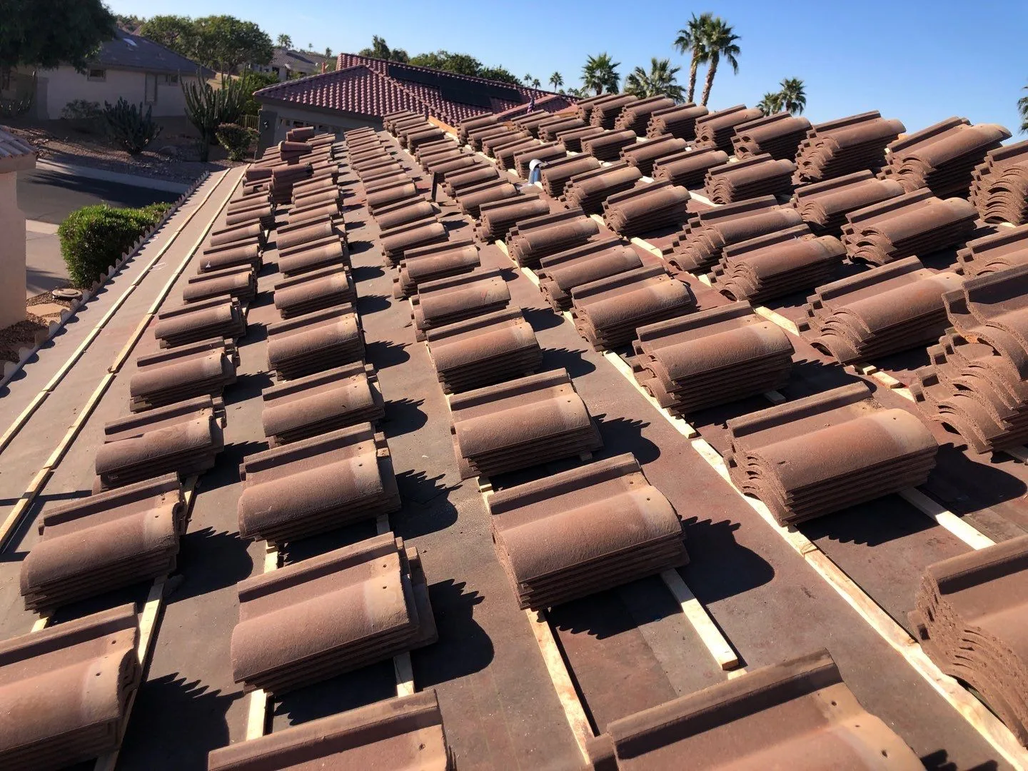 Roof-level view of terracotta-colored tiles staged in rows across exposed battens