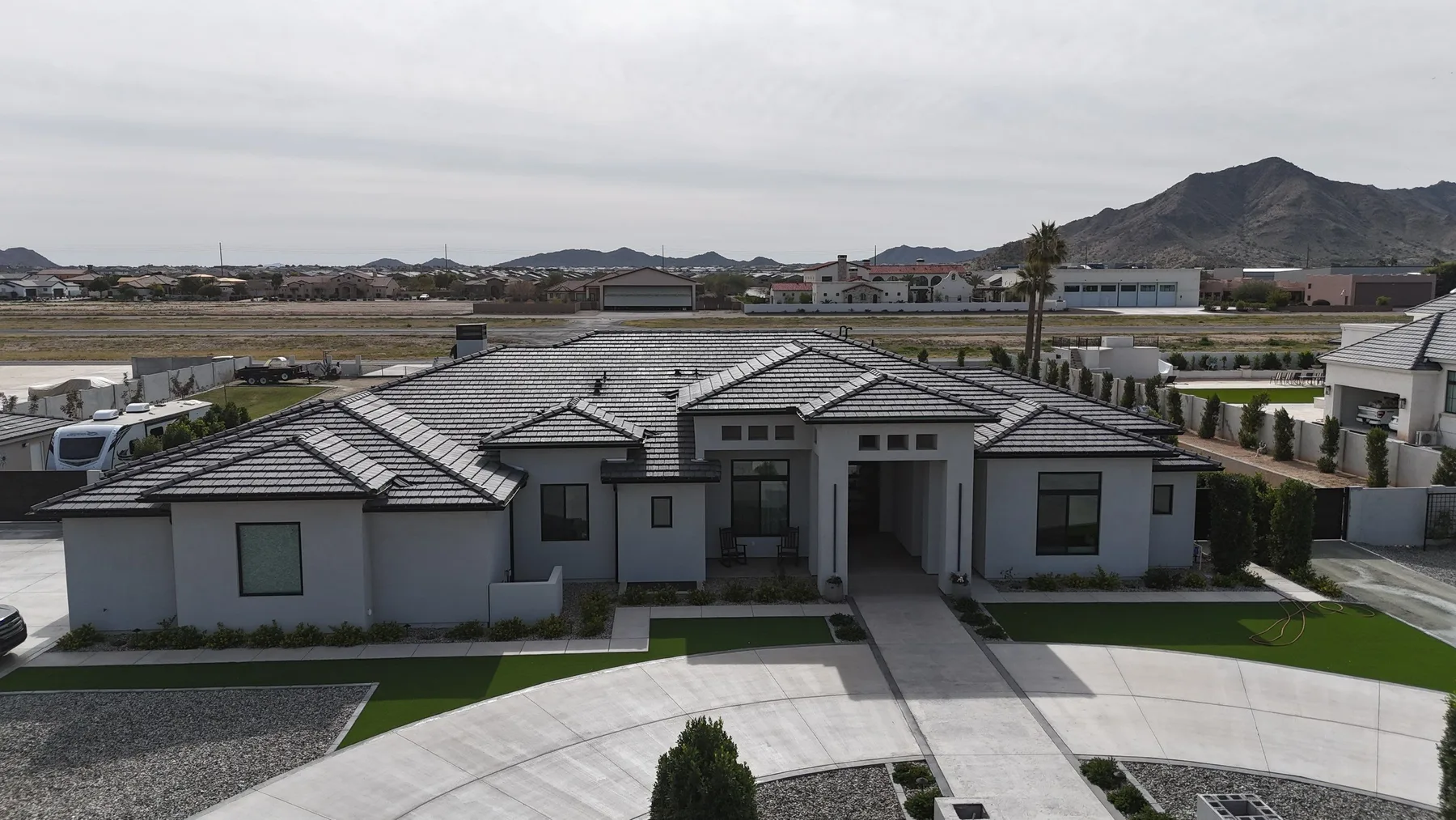 Elevated frontal view of completed gray tile roof above a broad symmetrical driveway