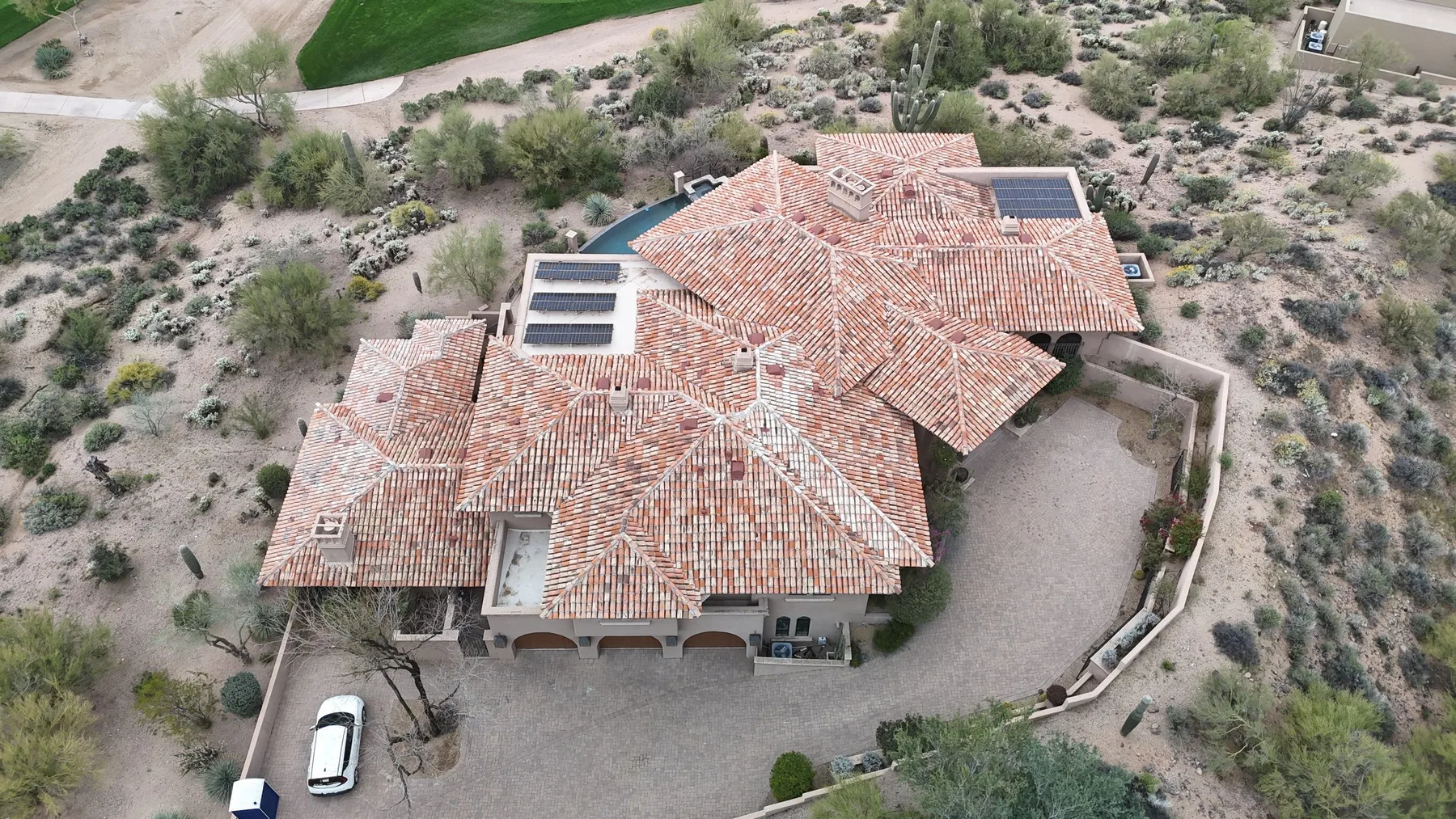 High aerial view of completed mottled red tile roof with dark rectangular panels