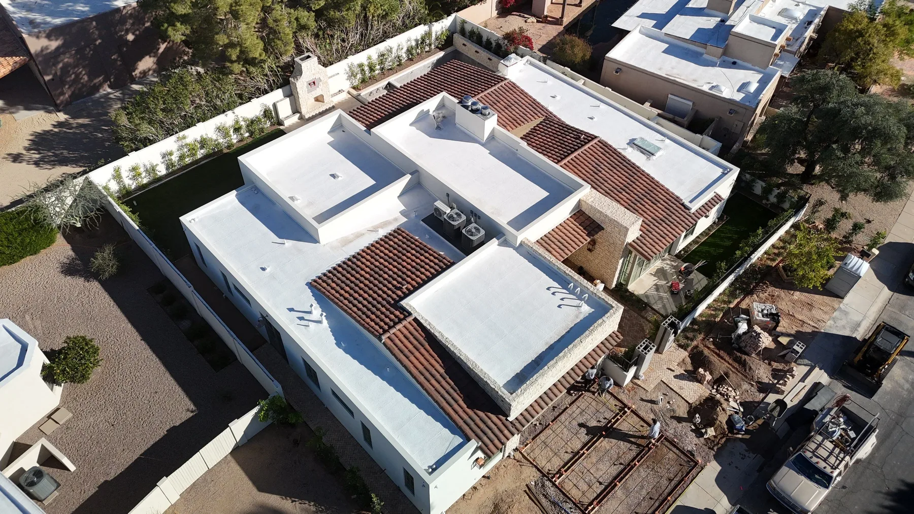 Oblique aerial view of white low-slope roofs bordered by narrow red tile sections