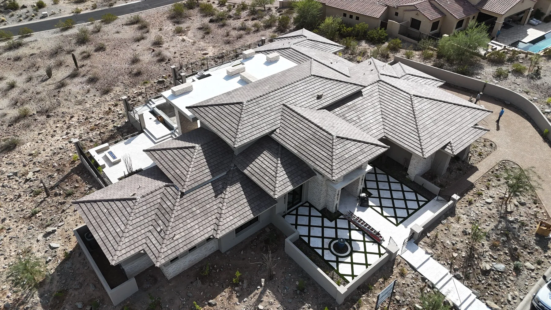 High oblique view of completed light gray tile roof with layered intersecting hips
