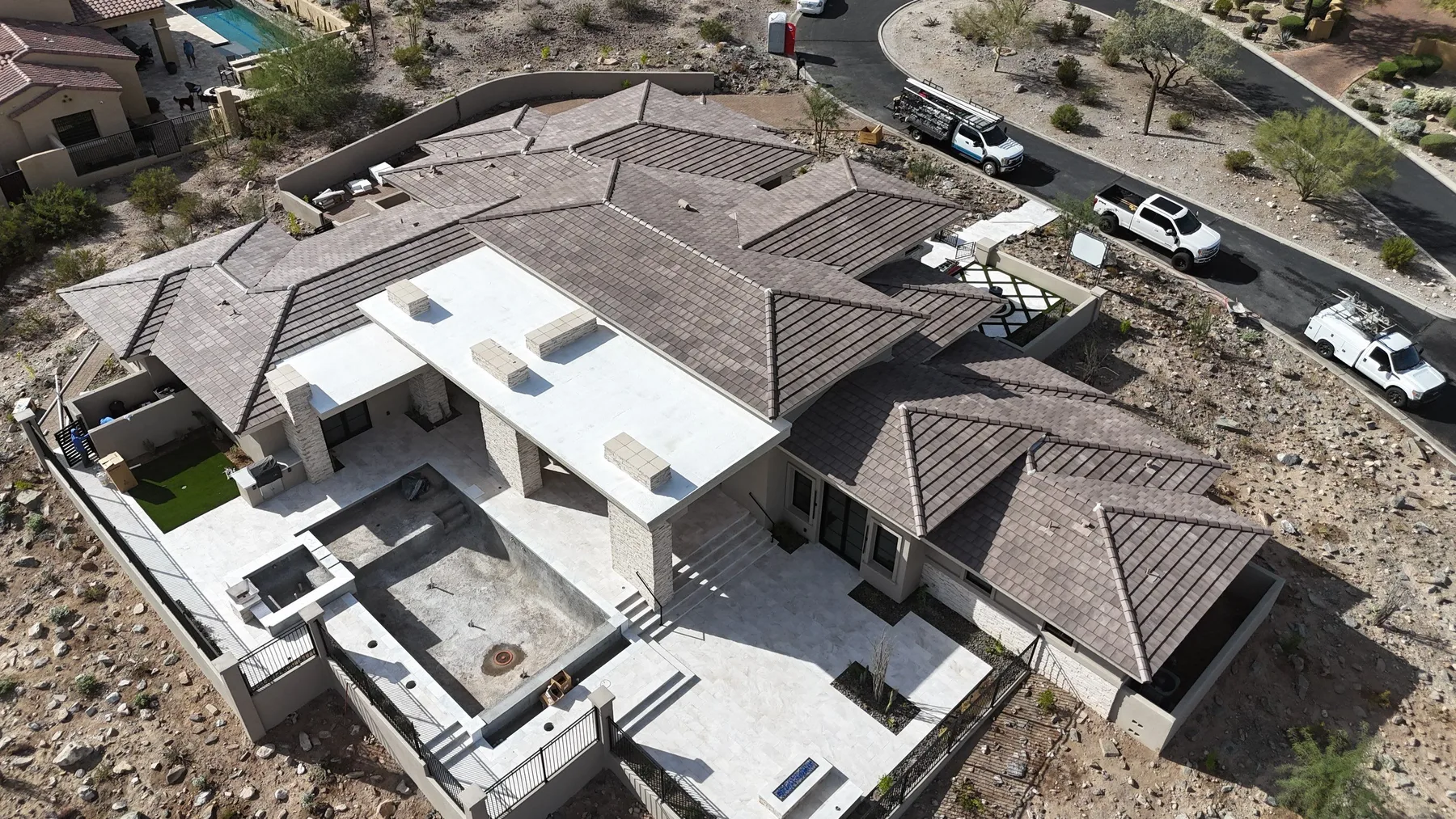 Oblique aerial view of brown-gray tiled hips surrounding broad white low-slope roof sections
