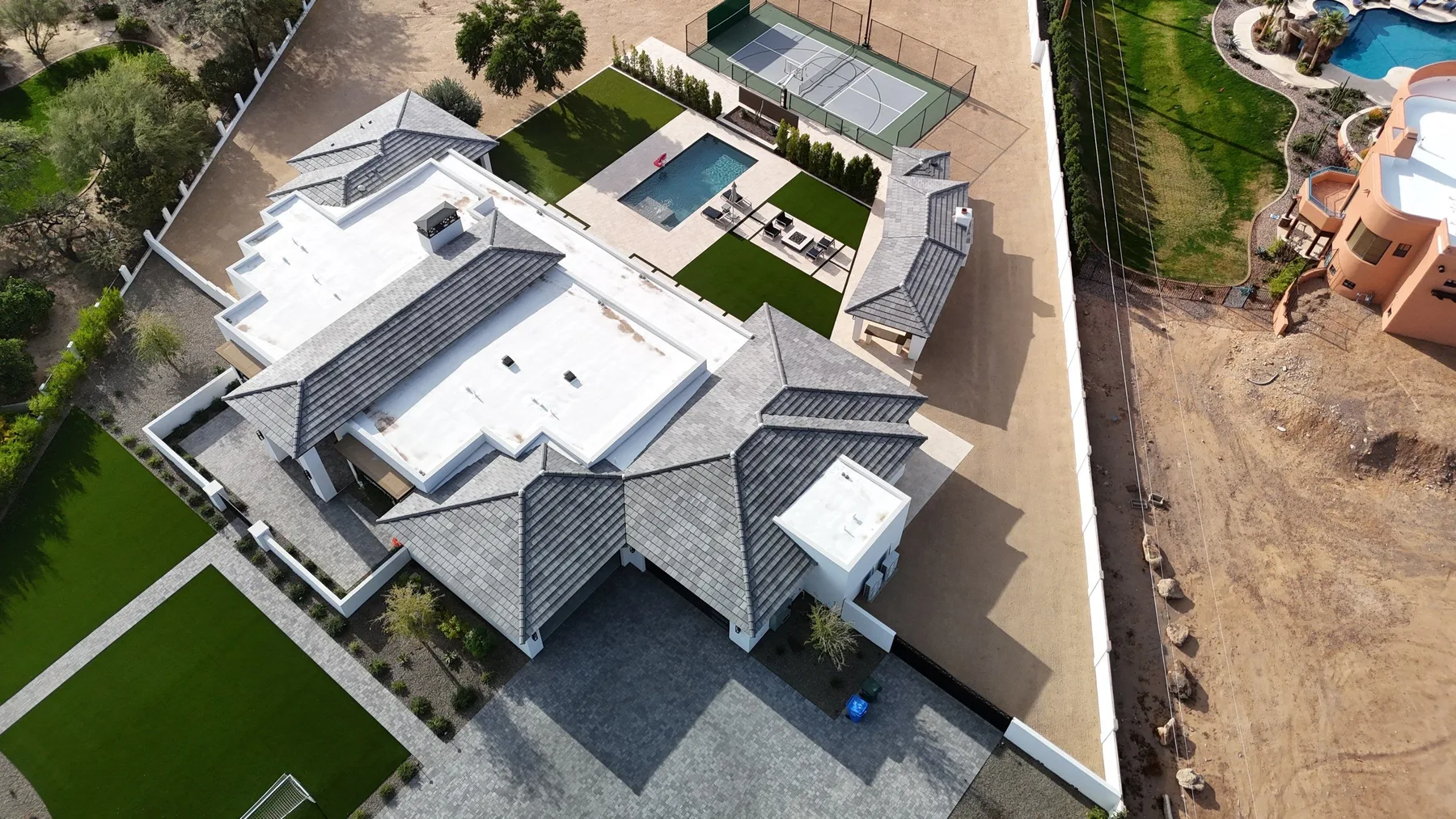 Top-down aerial view of gray tiled gables and white flat roof sections around courtyards