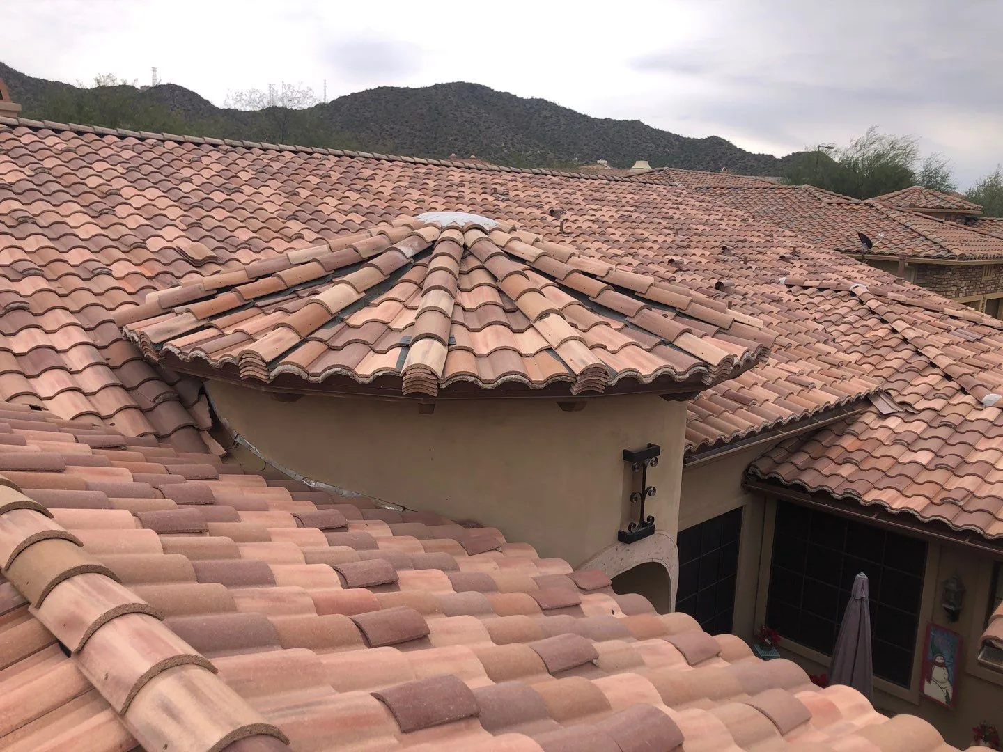Elevated view of completed reddish curved tile roofs with a rounded turret against mountains