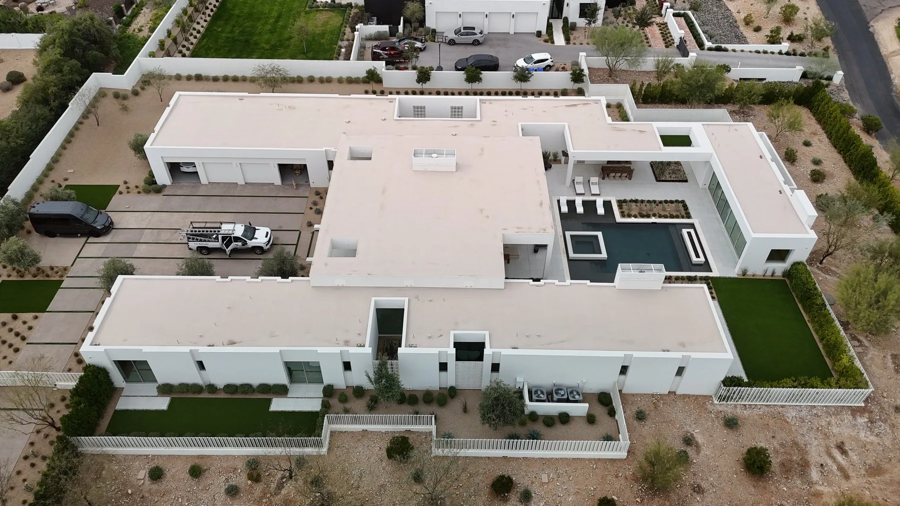 Top-down aerial view of expansive white flat roofs framing a dark rectangular courtyard