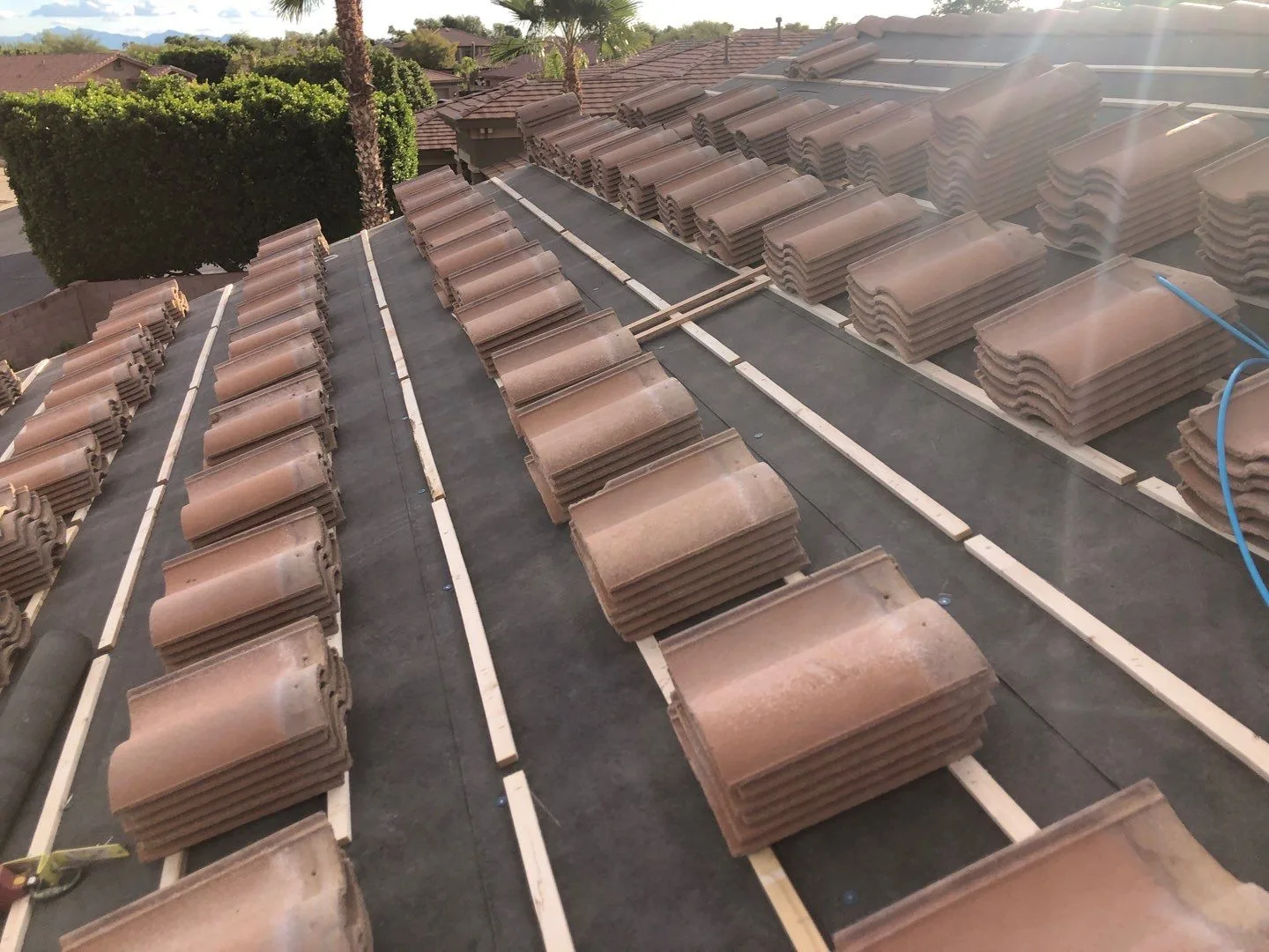 Close rooftop view of terracotta tiles stacked across black underlayment and battens
