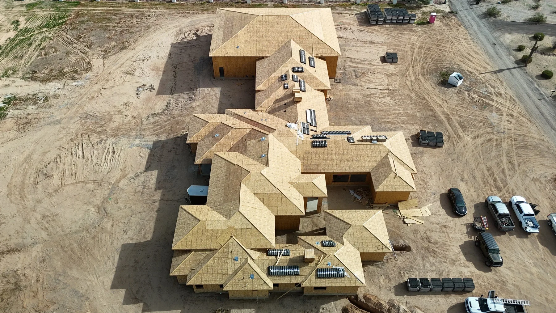 High aerial view of tan wood roof decking across a large multi-wing structure