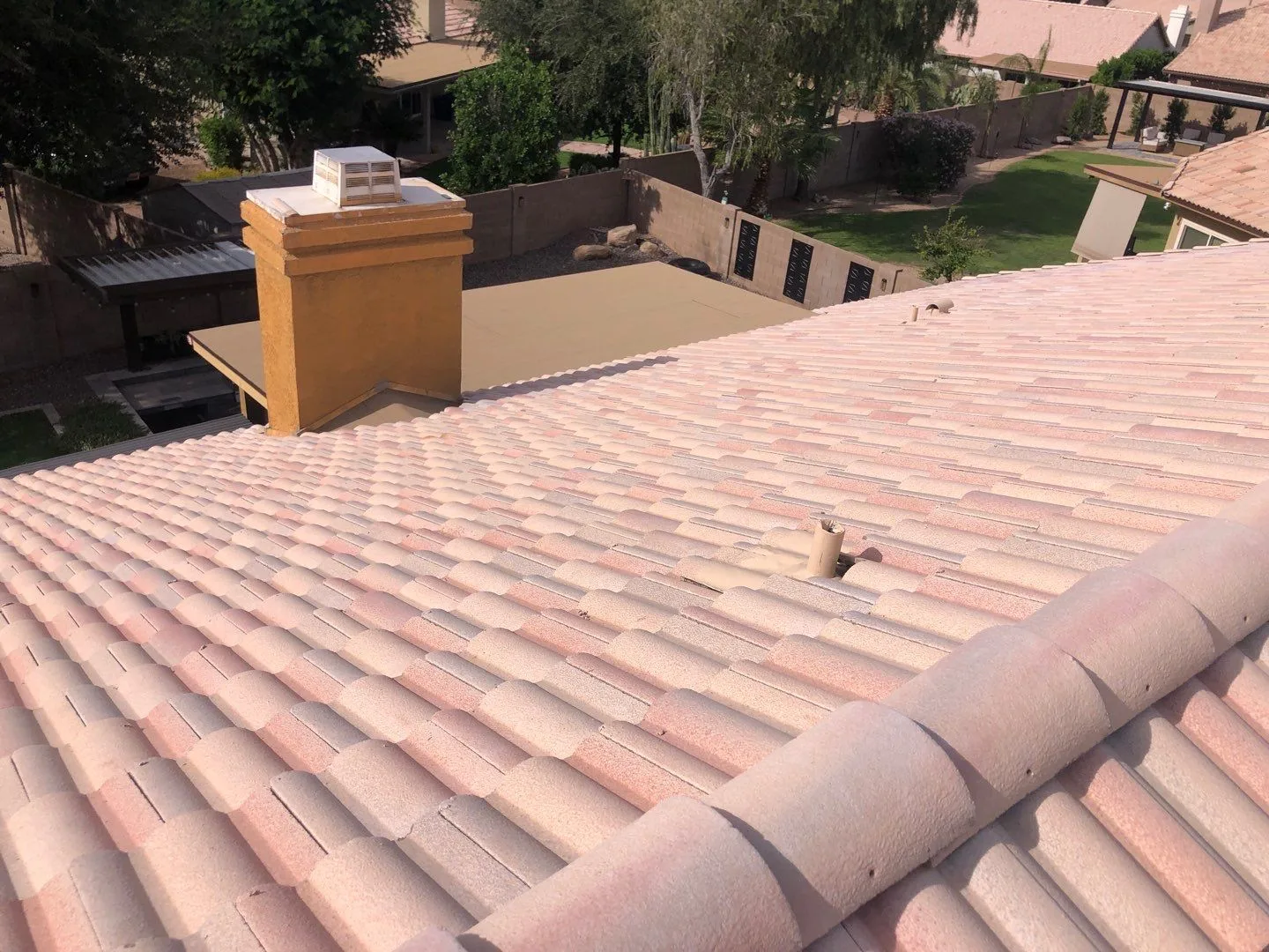 Elevated rooftop view of completed pale pink tiles surrounding a tan chimney
