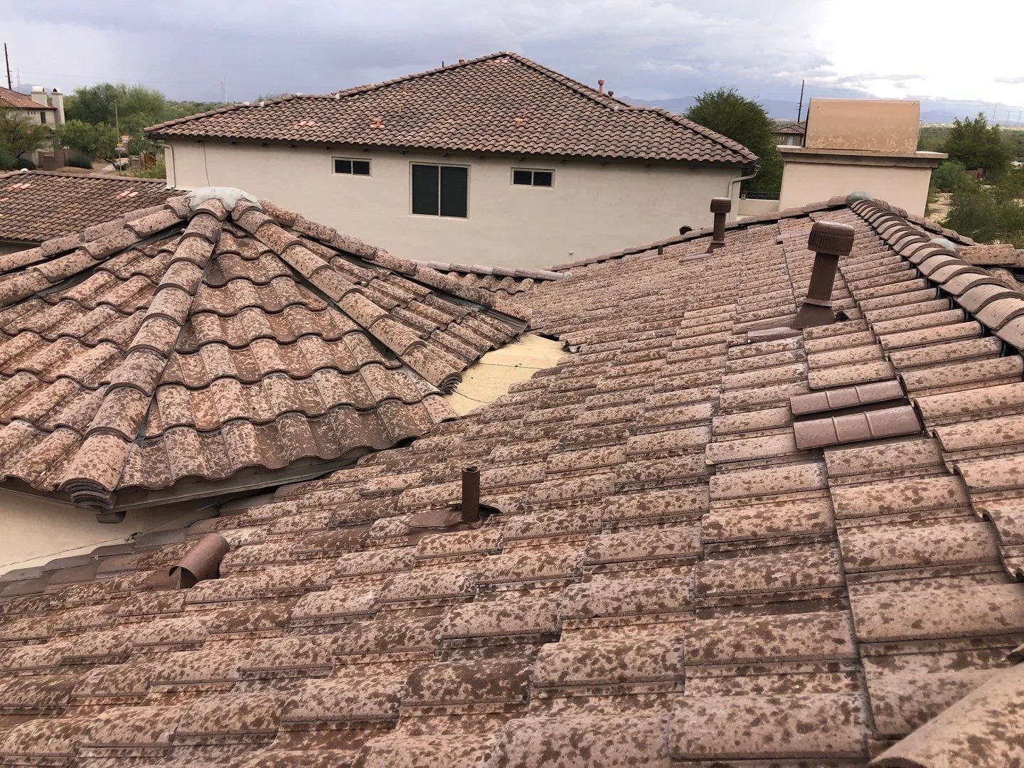 Rooftop view of completed mottled brown tiles across intersecting roof planes and vents