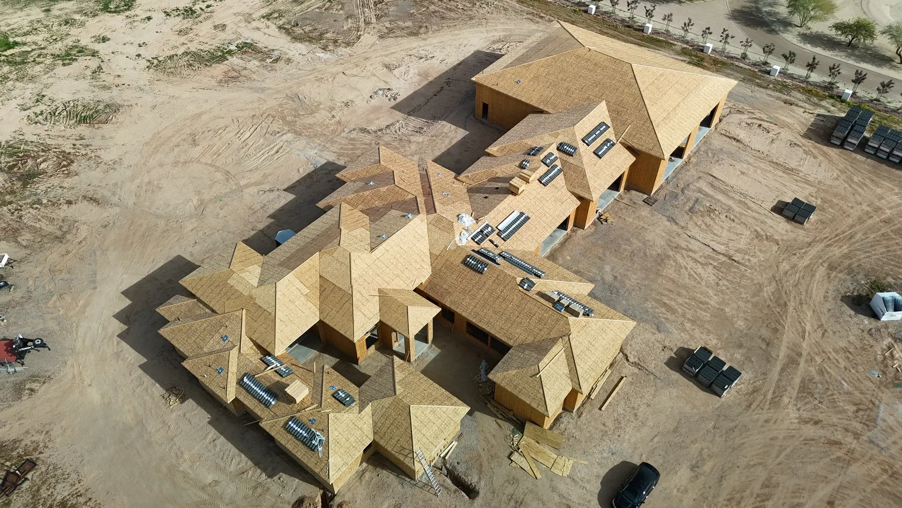 Oblique aerial view of unfinished tan roof decking with numerous gables and openings