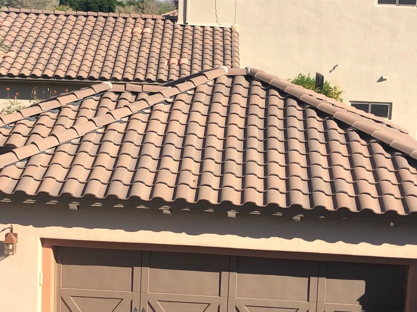 Elevated front view of completed peach-colored tiles on a hipped garage roof