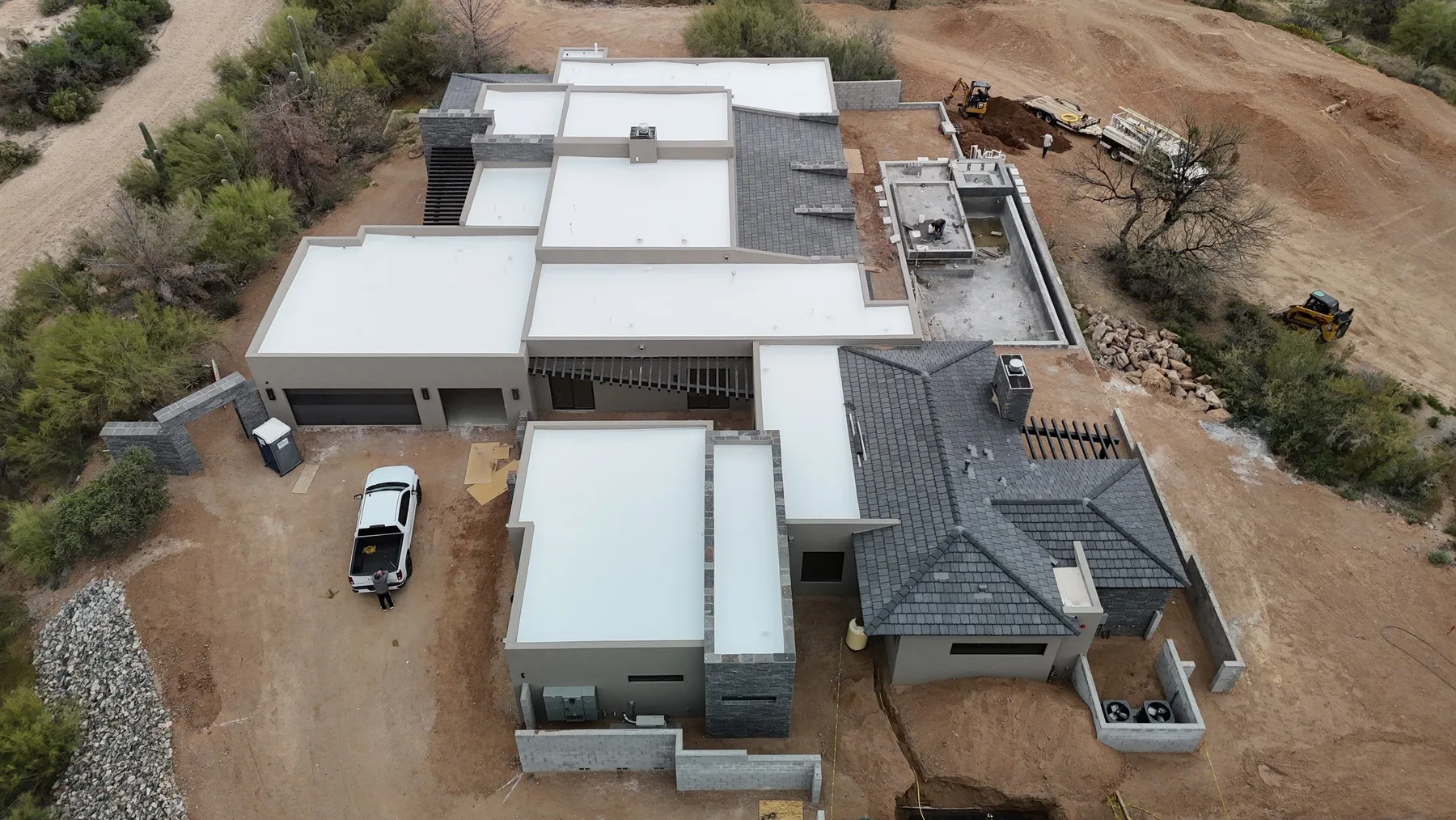 Oblique aerial view of white flat roofs adjoining a gray tiled hipped section