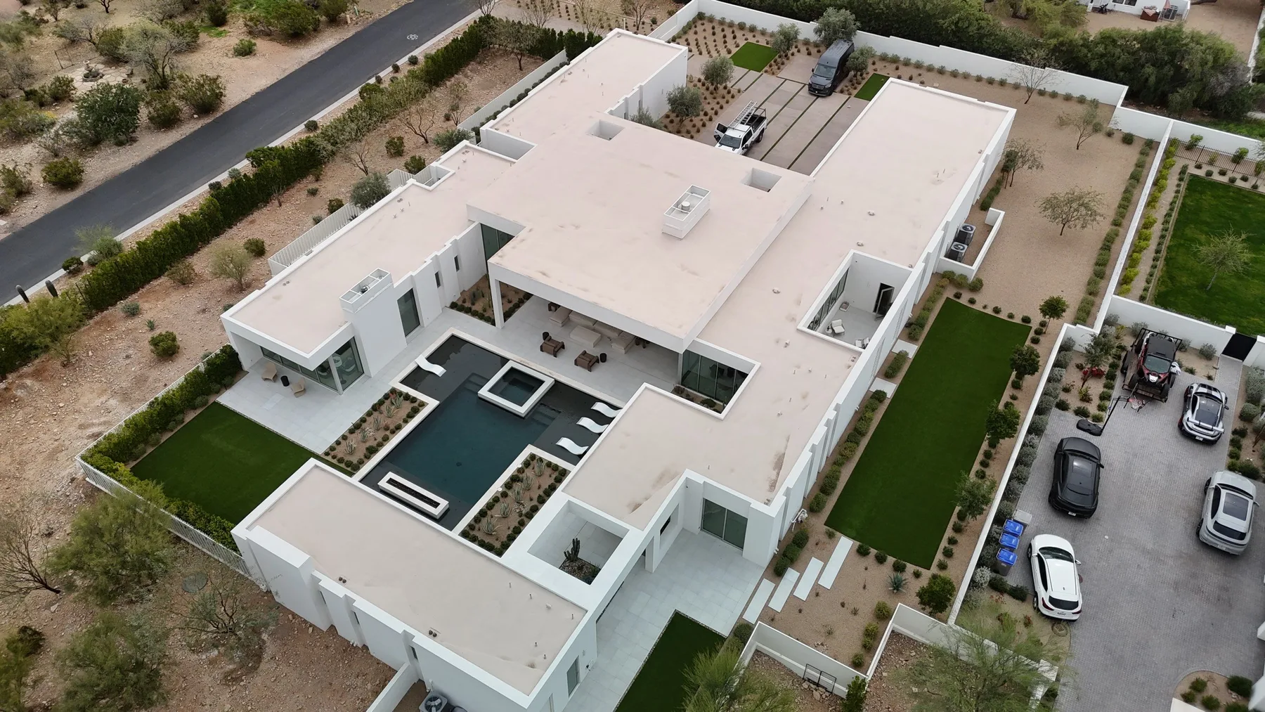High aerial view of expansive white flat roofing over a modern home with courtyards