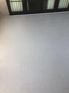 Downward view of finished white waterproofed deck beneath dark-framed glass doors