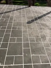 Downward view of finished gray rectangular walk-deck surface with white grid lines and pole shadow